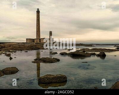 Bellissimo scatto di un faro nell'oceano durante un tramonto mozzafiato Foto Stock