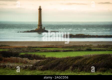 Bellissimo scatto di un faro nell'oceano durante un tramonto mozzafiato Foto Stock