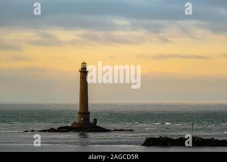 Bellissimo scatto di un faro nell'oceano durante un tramonto mozzafiato Foto Stock