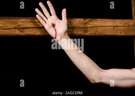 Vista ritagliata di Gesù crocifisso sulla croce di legno isolato su nero Foto Stock