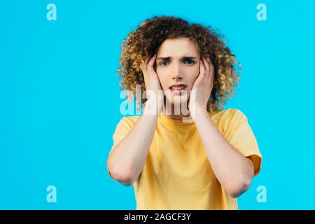 Ha sottolineato la parentesi adolescente che copre le orecchie con mani isolato su blu Foto Stock