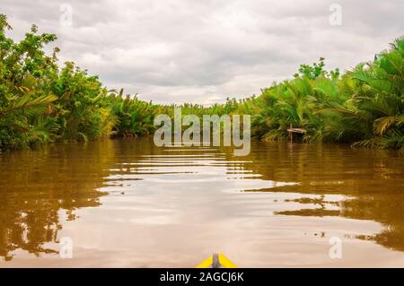 Un'immagine ad angolo basso di un lago sporco circondato da un paesaggio verde sotto il cielo nuvoloso Foto Stock