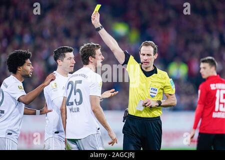 18 dicembre 2019, Baden-Wuerttemberg, Freiburg im Breisgau: Calcio - Bundesliga, SC Freiburg - FC Bayern Monaco, xvi giornata nella Foresta Nera Stadium. Arbitro Sascha Stegemann (secondo da destra) mostra Monaco di Baviera Thomas Müller (terza da sinistra) il cartellino giallo. Serge Gnabry (l) e Robert Lewandowski anche guardare. Foto: Uwe Anspach/dpa - NOTA IMPORTANTE: In conformità con i requisiti del DFL Deutsche Fußball Liga o la DFB Deutscher Fußball-Bund, è vietato utilizzare o hanno utilizzato fotografie scattate allo stadio e/o la partita in forma di sequenza di immagini e/o video-come photo se Foto Stock