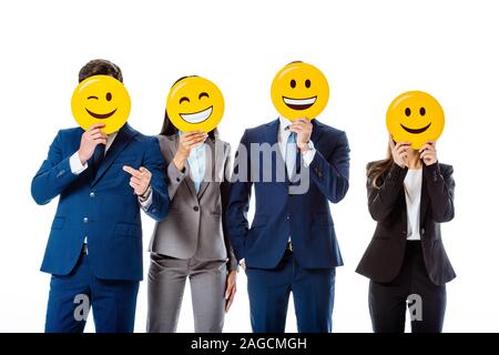 Kiev, Ucraina - 12 agosto 2019: business multiculturale di persone in giacca tenendo gli Emoji nella parte anteriore delle facce isolato su bianco Foto Stock