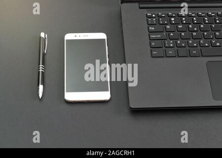 Penna, smartphone e computer portatile sul tavolo grigio, vista dall'alto in basso Foto Stock