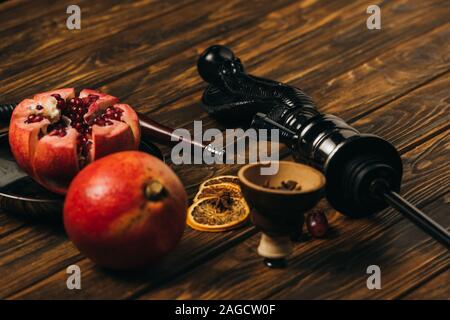 Hookah, granati, uve secche e tagliare le arance su una superficie di legno Foto Stock