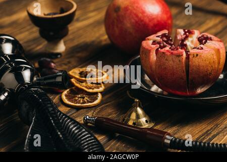 I granati, secchi Arance e narghilè su una superficie di legno Foto Stock