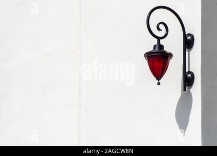 Lampada decorativa rossa appesa su una parete bianca in cemento - ottimo per uno sfondo fresco Foto Stock