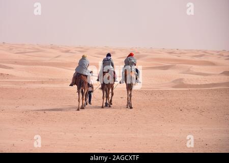 Cammelli caravan andando nel deserto del Sahara in Tunisia, Africa. I turisti di marcia il cammello safari. Camel caravan andando attraverso le dune di sabbia nel deserto del Sahara Des Foto Stock