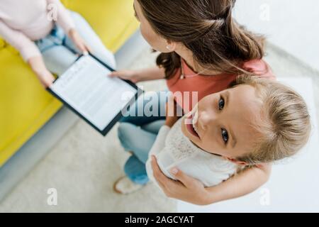 Vista aerea della madre in piedi con la figlia di felice e dando appunti al servizio di babysitter Foto Stock