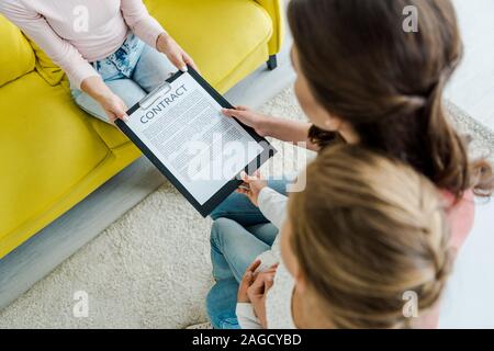 Vista aerea della madre in piedi con la figlia e dando appunti al servizio di babysitter Foto Stock