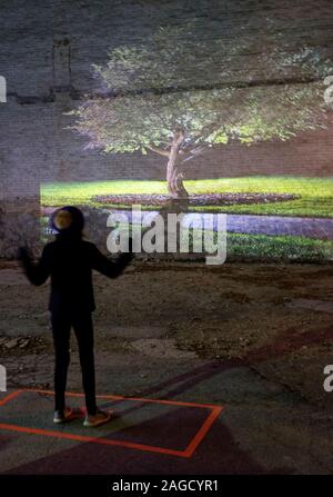 Un bambino interagisce con una immagine proiettata di un albero a La Nuit Blanche art festival nel distretto di scambio di Winnipeg, Manitoba Foto Stock