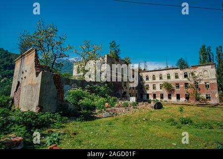 In rovina la scuola ricoperta in ghost città mineraria Akarmara, le conseguenze di una guerra in Abkhazia, verde post-apocalittico concetto. Foto Stock