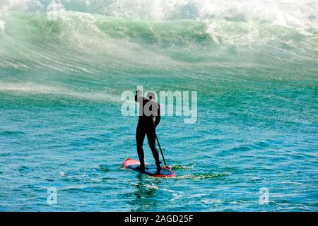 Surfer paddling verso un'onda. Foto Stock