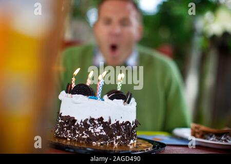Metà uomo adulto soffiando fuori candele su una torta di compleanno. Foto Stock