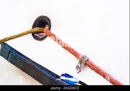 Hawsehole nero e giallo e rosso funi di ormeggio sul lato della nave bianca con spazio di copia Foto Stock