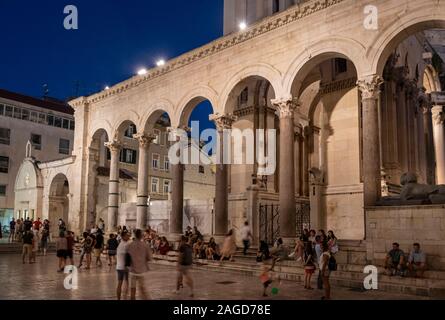 Persone di bere e di esplorare la plaza dentro il Palazzo di Diocleziano di notte, Split, Croazia Foto Stock