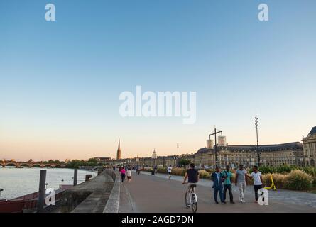 Passeggiata lungo il fiume Garrone con i camminatori e ciclisti al tramonto, città di Bordeaux, Francia Foto Stock
