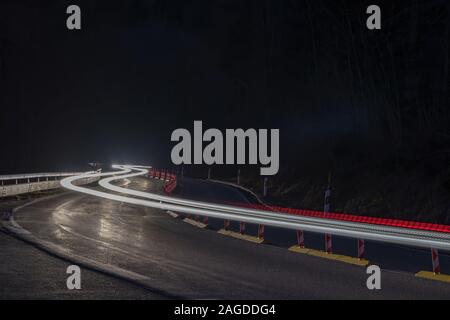 Auto sentieri dei fari sulla curva road Foto Stock