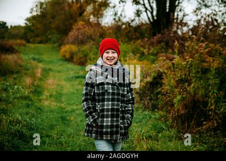 Giovane ragazza che indossa un cappotto a scacchi camminare per un percorso di paese Foto Stock