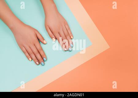 Manicure nei colori più alla moda: corallo, metallici giallo e menta su sfondo colorato. Piatto stile di laici. Foto Stock