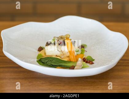 Delizioso piatto di pesce fatto con diversi tipi di verdure su una superficie di legno Foto Stock