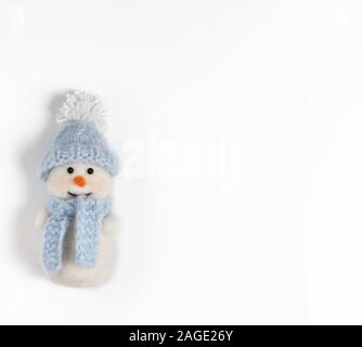 Carino divertente pupazzo di neve in blu cappello e sciarpa su sfondo bianco. Natale giocattolo di lana. Copia dello spazio. Felice anno nuovo. Concetto di inverno. Biglietto di auguri. Foto Stock