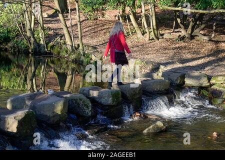 Donna attraversando pietre miliari, Endcliffe Park, Sheffield, Yorkshire, Inghilterra, Regno Unito Foto Stock