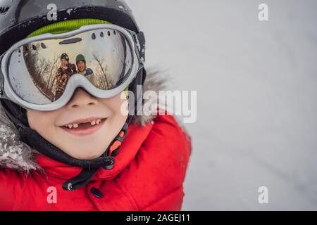 Mamma e papà si riflettono nel ragazzo occhiali da sci. Mamma e papà di insegnare a un ragazzo di sci o di snowboard Foto Stock