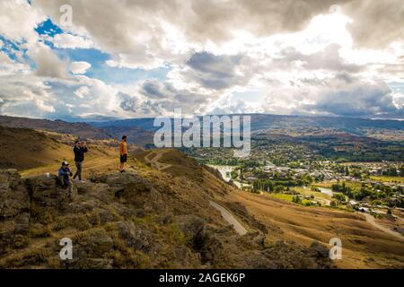 Alexandra, Otago, Nuova Zelanda, 9 Dicembre 2019: turisti guardano Alexandra dal punto di vedetta su scogliere circostanti Foto Stock