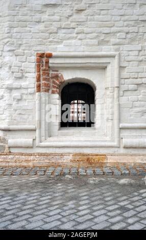 Finestra con grata nel vecchio muro di mattoni della chiesa Foto Stock