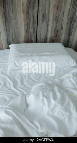 Un letto singolo con biancheria bianca e piumini che vengono utilizzati e accartocciata. Foto Stock