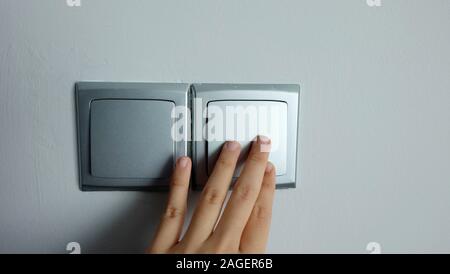 Una mano premendo su un interruttore a parete. Foto Stock