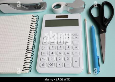 Articoli di cartoleria con calcolatrice bianco giacciono sul tavolo blu epty moderno Foto Stock