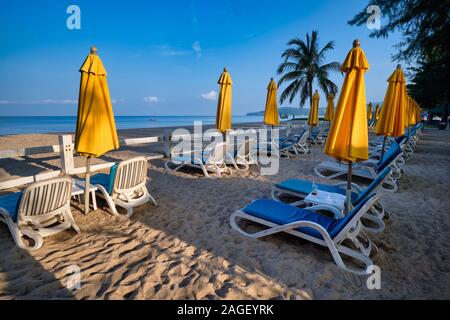 In un inizio di mattina a Bang Tao Beach, Phuket, Thailandia, sedie a sdraio e gli ombrelloni ancora inutilizzati stand Foto Stock