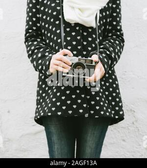 Giovane donna parigamba holding vintage fotocamera. Retrò fotocamera in mano ragazza closeup. Vecchia fotografia di moda concetto. Foto Stock