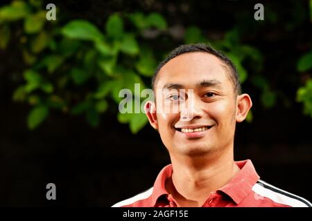 Bello e sano del Sudest Asiatico Adulto Giovane Uomo in camicia casual cercando e sorridente Foto Stock