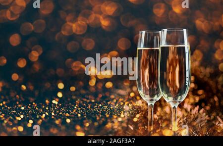 Due bicchieri di champagne su golden bokeh sfondo. Anno nuovo e di natale di lusso celebrazione di partito. Vini spumanti anno nuovo 2020 sfondo layout design. Foto Stock