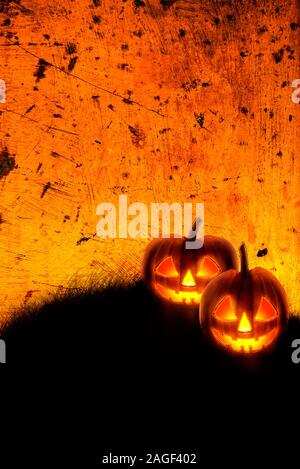 Halloween sfondo con jack o lantern scary zucche su grunge textured sfondo arancione. Festa di Halloween invito il layout di progettazione. Foto Stock