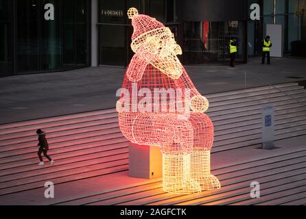 Wolfsburg, Germania. Xviii Dicembre, 2019. Un enorme illuminata Santa Claus si siede nell'Autostadt sulla banca del Mittelland Canal. In meno di una settimana, sarà la vigilia di Natale. Credito: Friso Gentsch/dpa/Alamy Live News Foto Stock