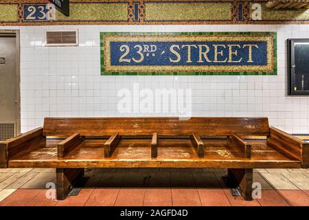 Vecchia panca di legno e vintage simbolo metropolitana a 23rd Street Subway Station, Manhattan, New York, Stati Uniti d'America Foto Stock