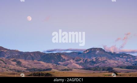 Quasi Full Moon Rising sulle colline e valli, San Simeone, California Foto Stock