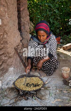 Etiopia, Amhara Region, Lalibela, città storica, donna fresco di tostatura i chicchi di caffè per rendere la buna Foto Stock