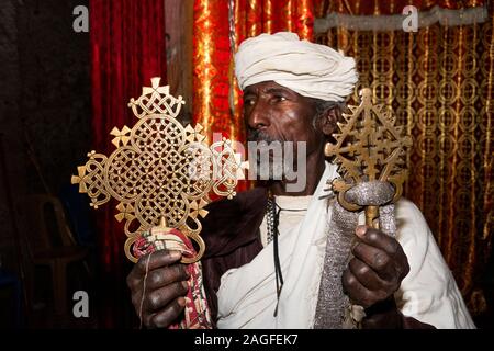 Etiopia, Amhara Region, Lalibela, Arbatu Ensessa, Biblia Chirkos, antiche rocce scavate chiesa, il sacerdote tiene due di bronzo la preghiera attraversa utilizzato in massa Foto Stock