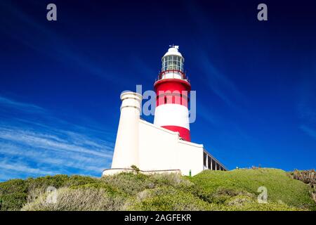 Il rosso e bianco faro di Cape Agulhas in una giornata di sole con cielo blu chiaro, Sud Africa Foto Stock