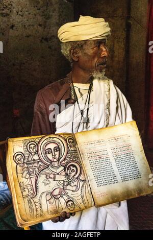 Etiopia, Amhara Region, Lalibela, Arbatu Ensessa, Biblia Chirkos, antiche rocce scavate chiesa, sacerdote mostra 800 anno-vecchio vangelo illuminato in Ge'ez s Foto Stock