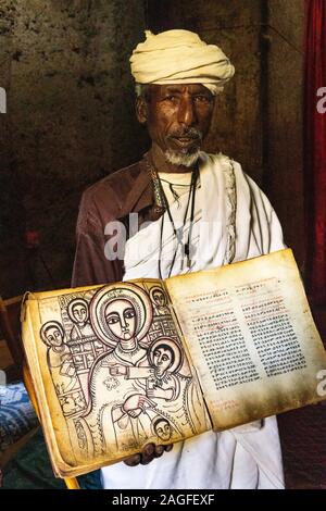 Etiopia, Amhara Region, Lalibela, Arbatu Ensessa, Biblia Chirkos, antiche rocce scavate chiesa, sacerdote mostra 800 anno-vecchio vangelo illuminato in Ge'ez s Foto Stock