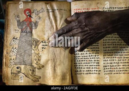 Etiopia, Amhara Region, Lalibela, Arbatu Ensessa, Biblia Chirkos, antiche rocce scavate chiesa, sacerdote la mano su 800 anni vangelo illuminato mostra Foto Stock