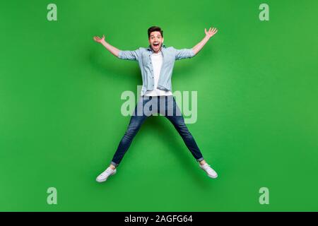 Full Size foto del bel ragazzo alto salto in forma di stella celebrare la competizione sportiva il primo posto vincendo indossare jeans casual outfit verde isolato Foto Stock