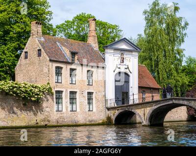 Cancello di ingresso al Begijnhof, beghinaggio e il ponte sul canale in Bruges, Belgio Foto Stock